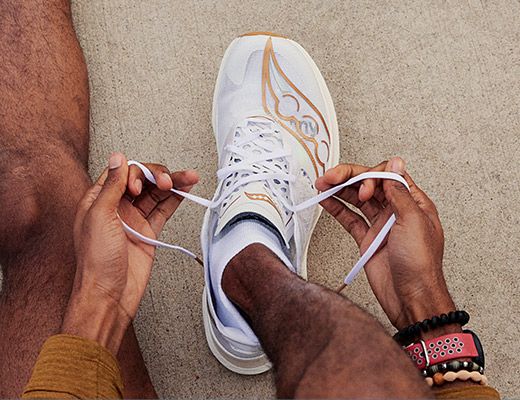 A person tying Saucony running shoe lace.