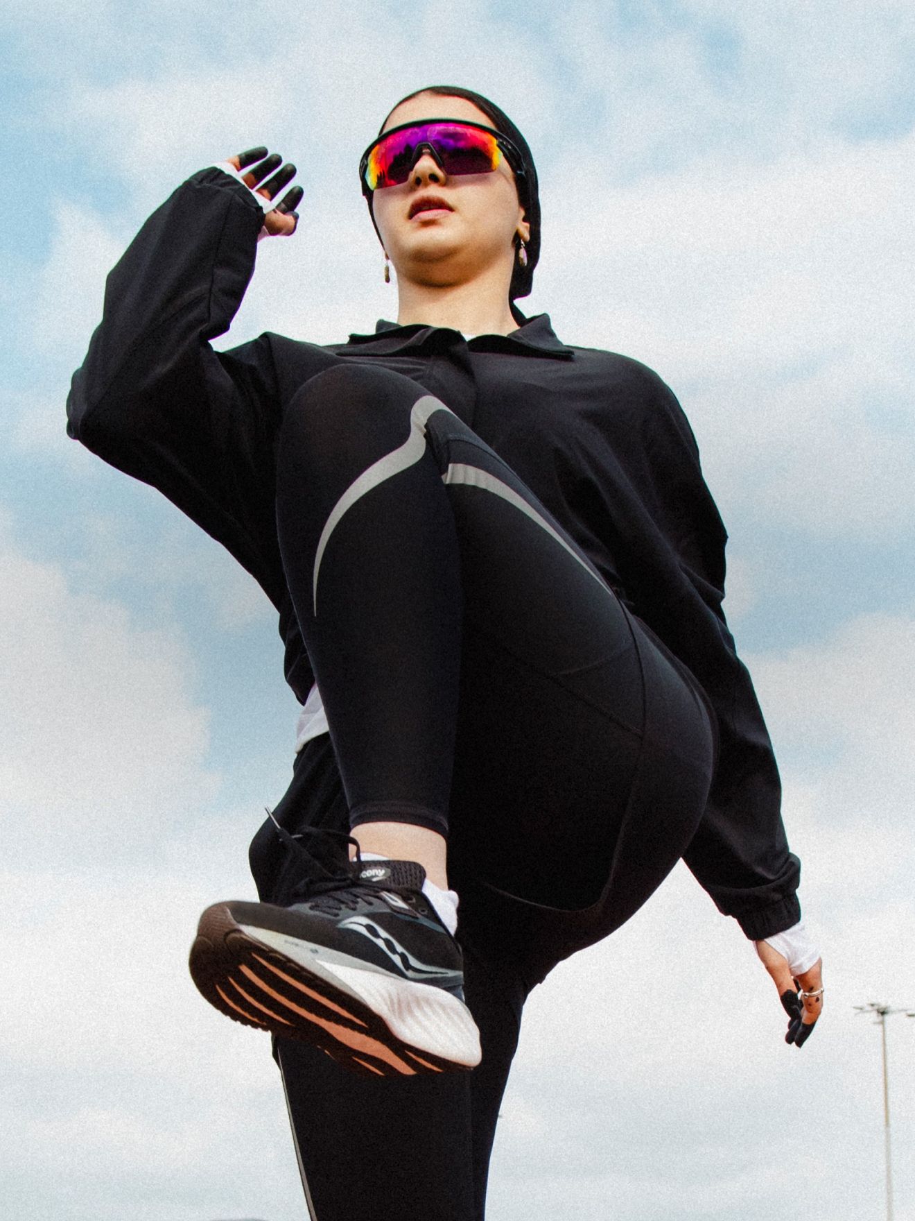 a person in black outfit and sunglasses jumping in the air