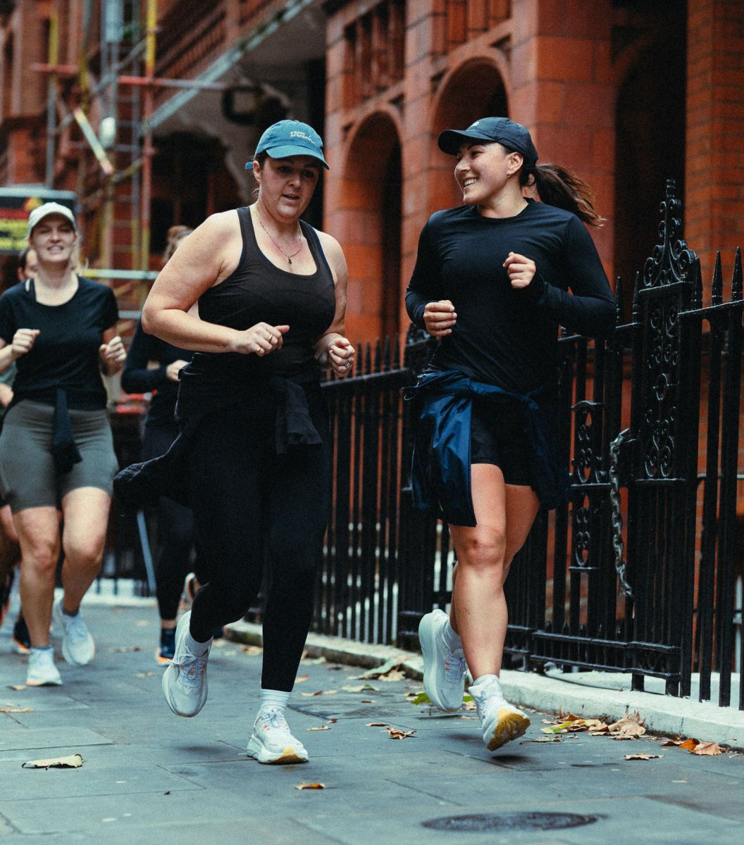 a group of women running on a sidewalk