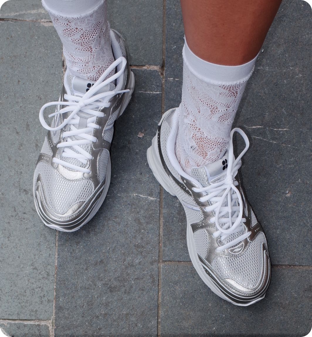 a person's feet wearing white socks and silver shoes