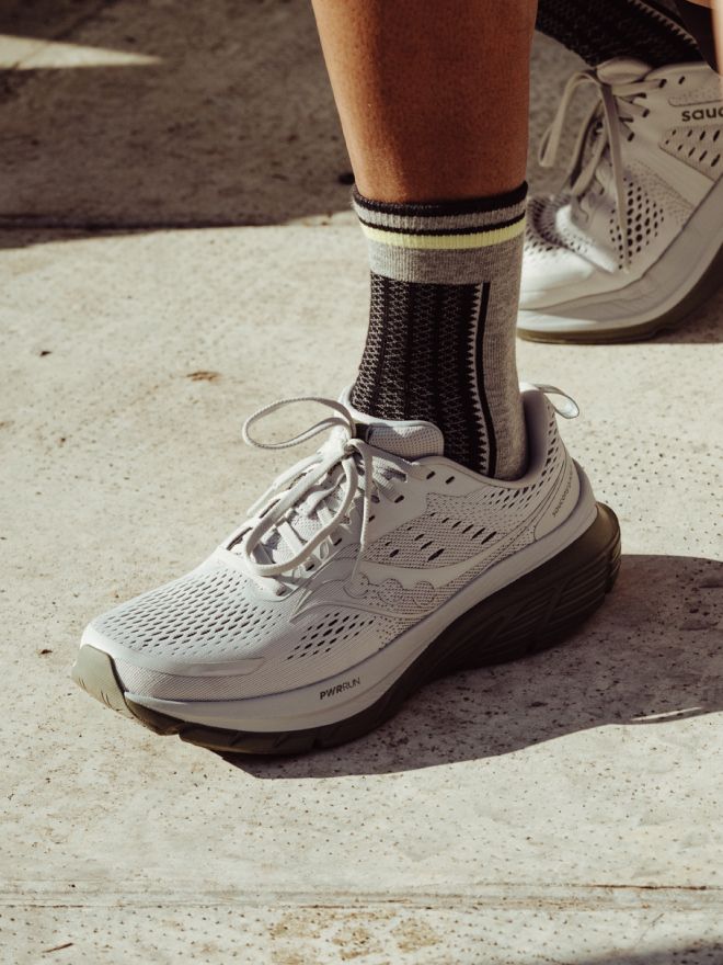 a person's feet wearing white shoes and a sock