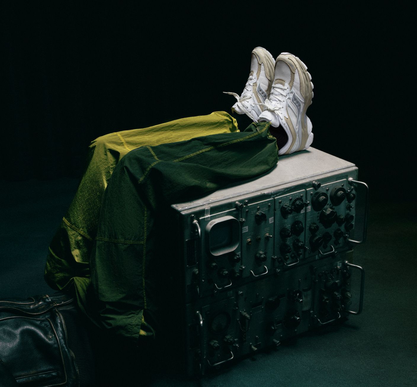 a pair of white sneakers on a metal box with a green jacket